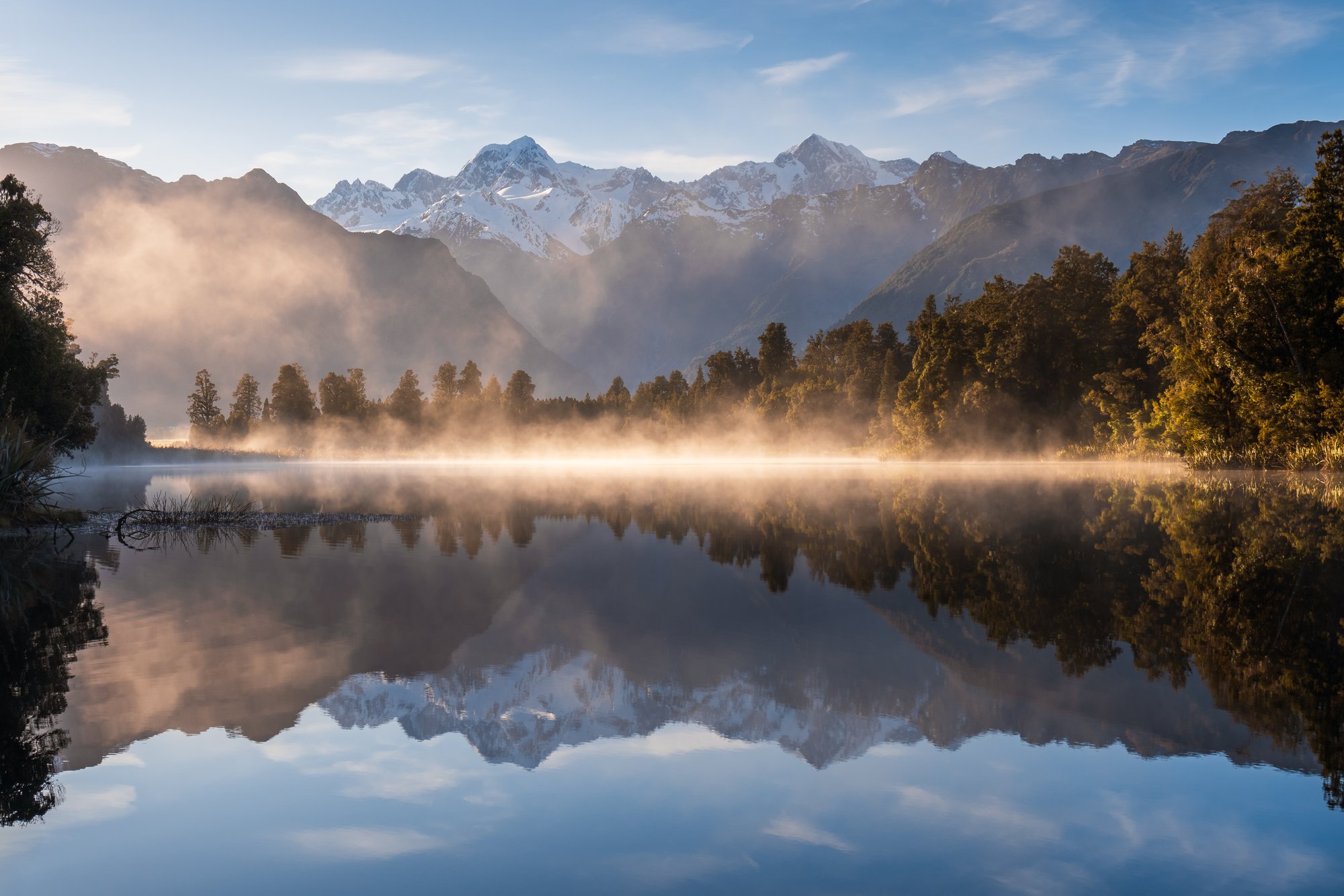 Lake Matheson s odrazem Aoraki a Mount Tasman při východu slunce. Tvoje fotka ze čtvrtého pokusu.
