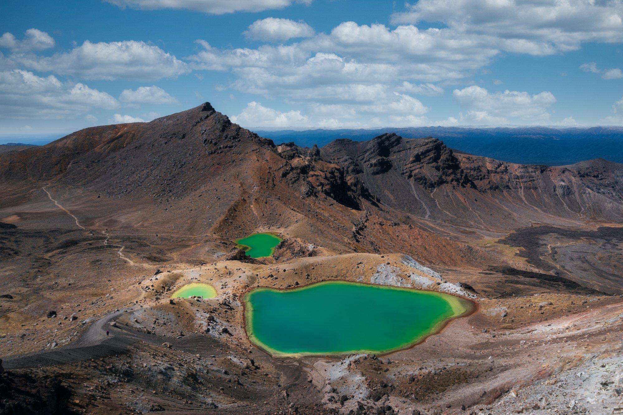 Emerald Lakes na Tongariro Crossing, nebo geotermální pára v Rotorui.