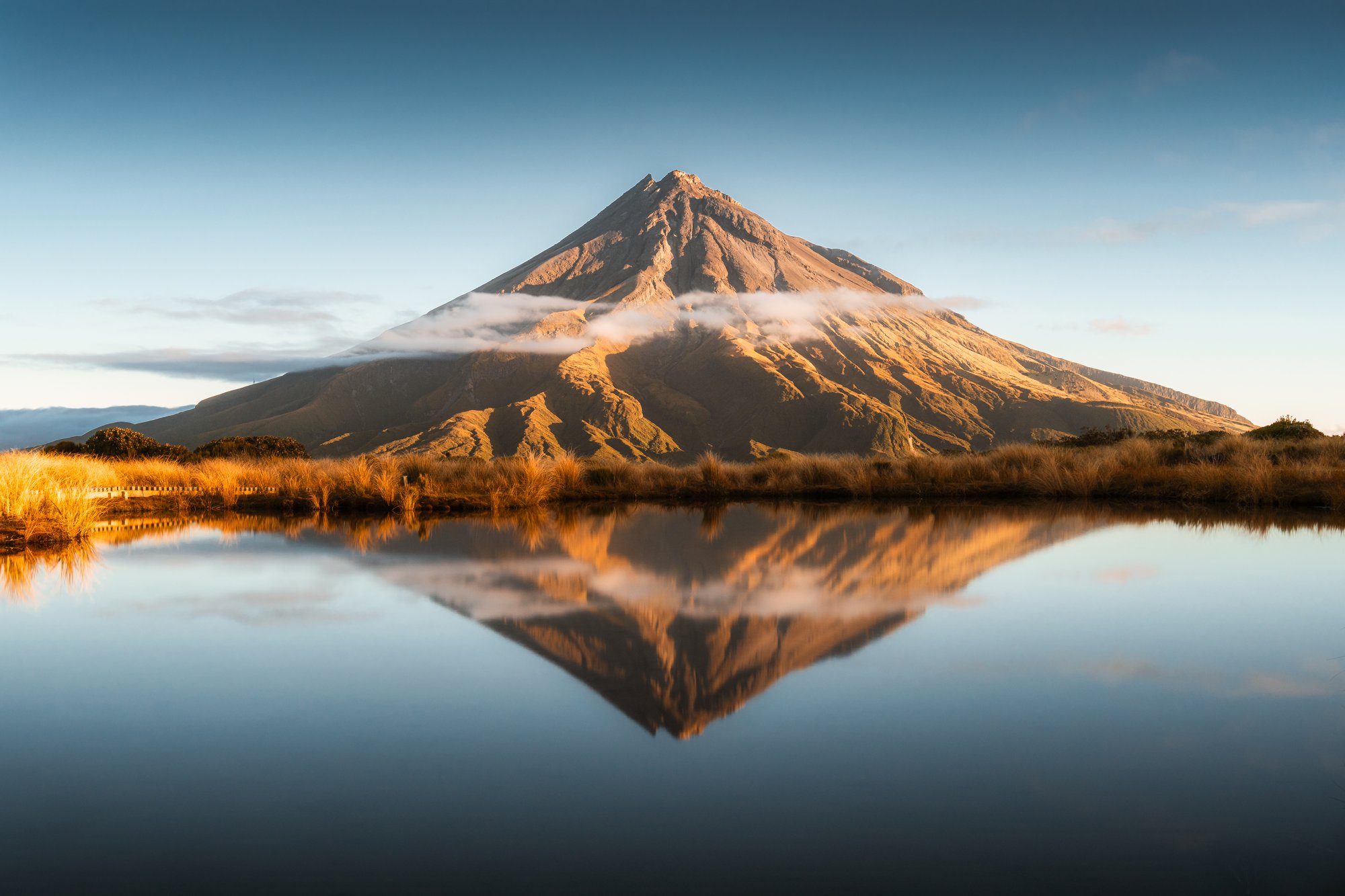 Taranaki odražený v jezírku Pouākai, nebo kužel hory nad ranní mlhou.