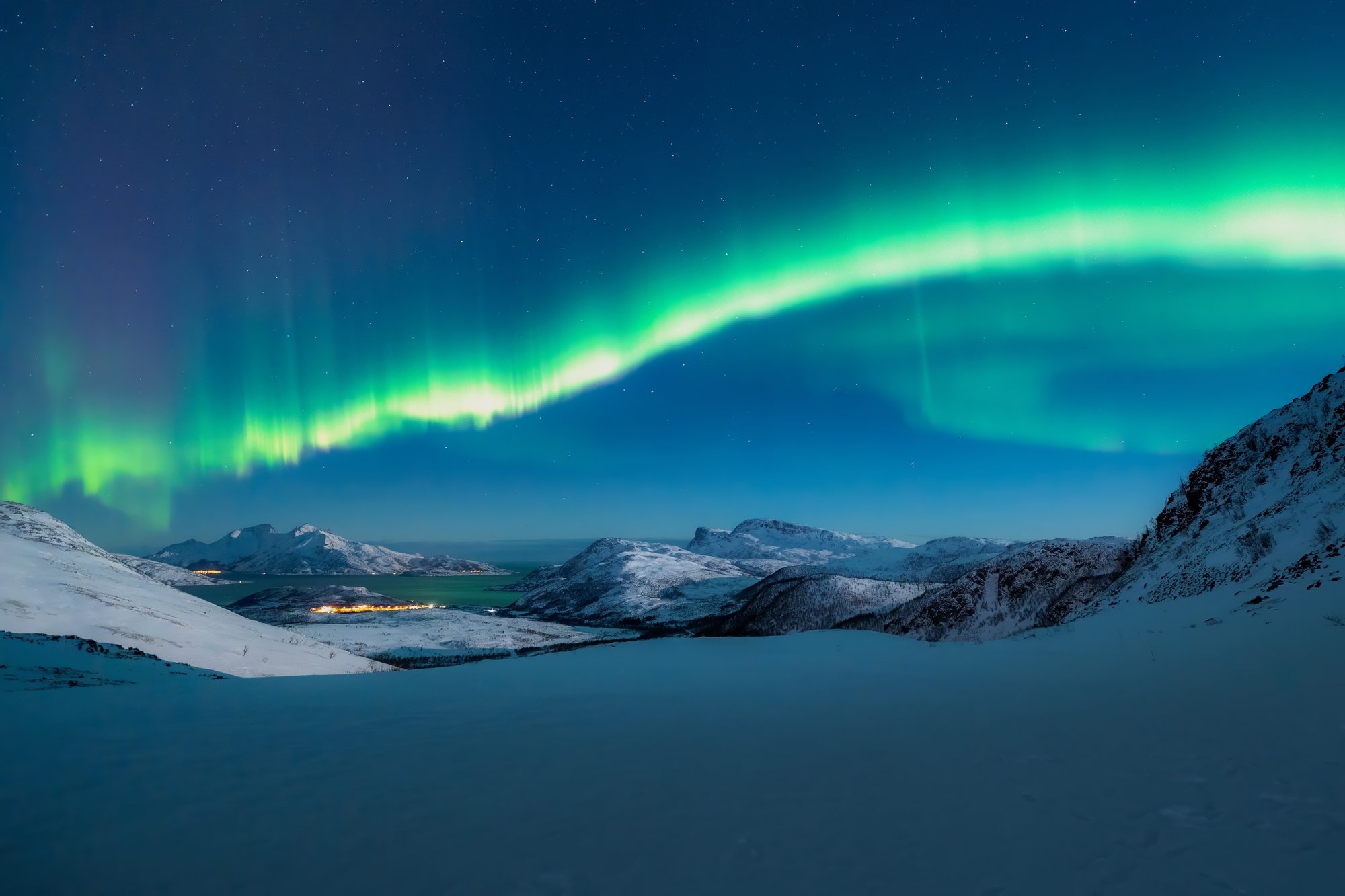 aurora nad fjordem, širší záběr s horizontem, ideálně s odrazem ve vodě.