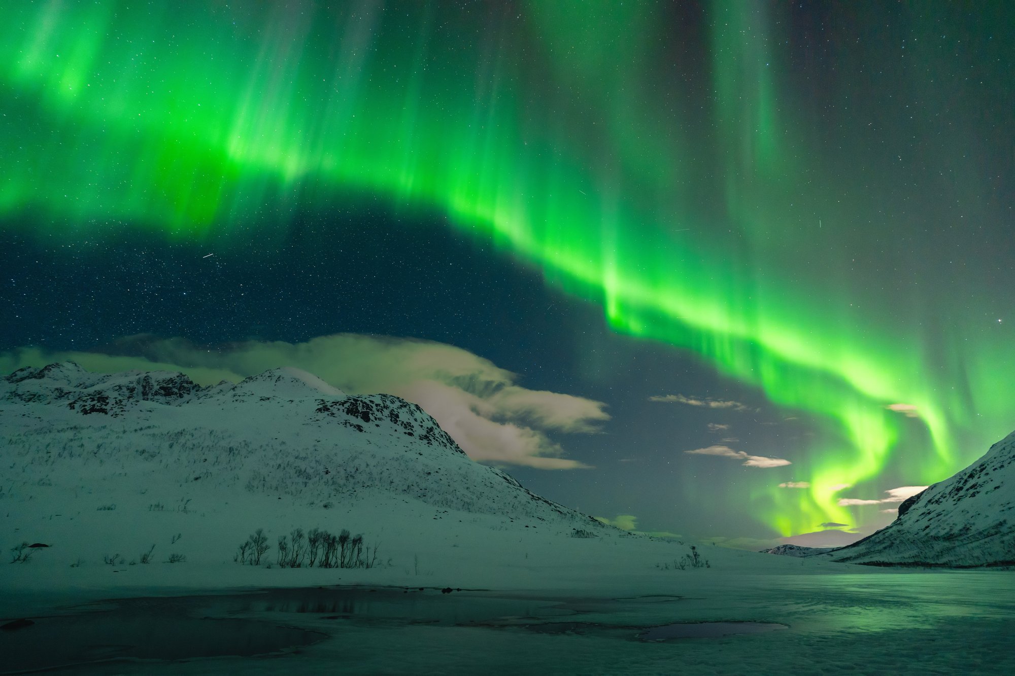 aurora nad pobřežím Kvaløyi nebo u Sommarøy, širokoúhlý záběr s horami.